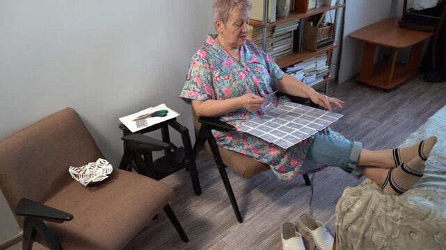 Elderly woman is playing a card game of solitaire.