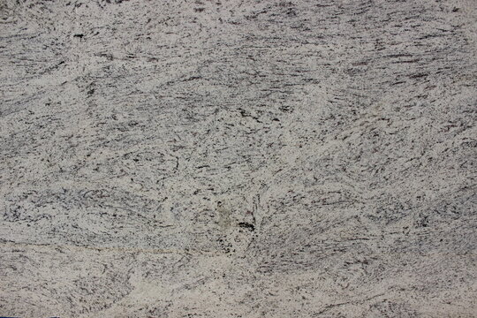 Detail of white granite texture with evenly distributed small grey mineral grains, durable natural stone for exterior floors and walls.