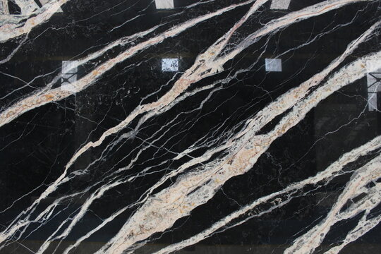 Luxurious black Portoro marble with thick gold and white veins crossing the stone surface.