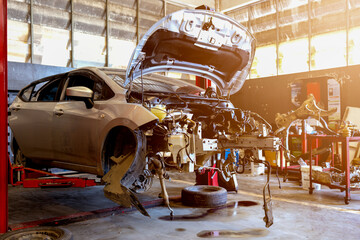 Car on hydraulic lift in auto repair shop with front body removed for engine and chassis service.