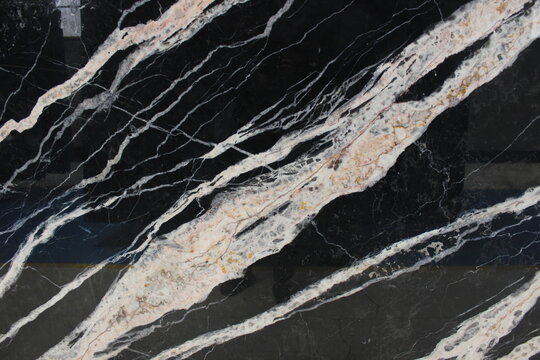 Detail of black Portoro marble showing gold and white mineral crystallization in dynamic patterns.
