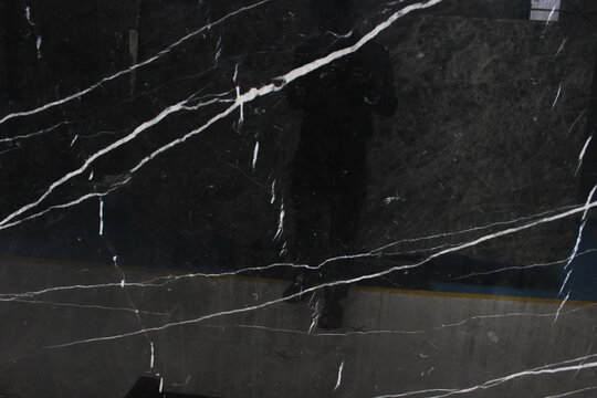 Black Nero Marquina marble with light reflections on the polished surface showing bold white veins.
