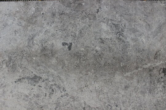 Texture of Tundra Grey marble with a soft grey base and scattered dark mineral spots providing a calm and natural impression.