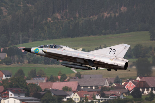 Zeltweg, Austria - September 3, 2022: AIRPOWER22 - Historic Swedish Air Force Saab SK 35C Draken fighter jet flying low over village.