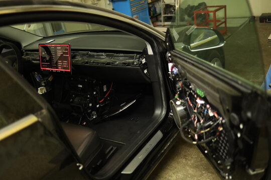 KYIV, UKRAINE - NOV 18, 2025: Mechanic repairing a window regulator motor inside the door panel of a Tesla Model 3.
