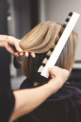 Close up professional colorist selecting perfect hair dye shade from color palette. Focus on hands and swatches for color match before coloring service