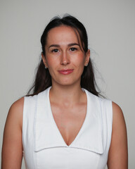 Obraz premium Front image closeup of a brunette young woman with make-up, in a dress, posing in studio, over grey background. 