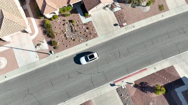 Aerial view of a white SUV driving through a southwestern suburban neighborhood and pulling into a driveway