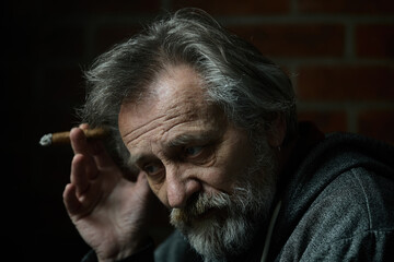 Senior bearded man smoking on balcony classic big cigar in detail