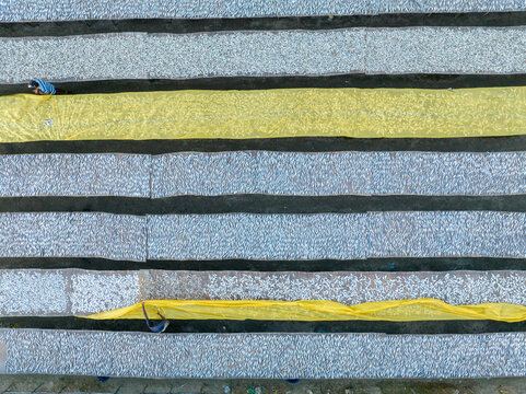 Aerial view of drying fishes on the beach with vibrant yellow nets contrasting against the gray sand, Cox's Bazar, Chittagong Division, Bangladesh.