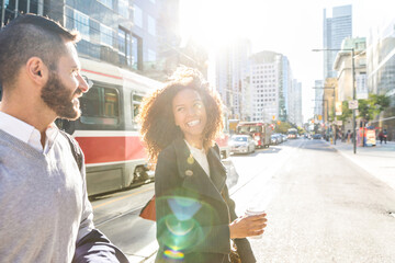 Obraz premium Happy diverse couple walking urban city street in morning sun
