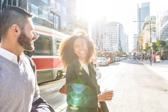 Happy diverse couple walking urban city street in morning sun