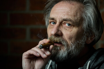 Senior bearded man smoking on balcony classic big cigar in detail