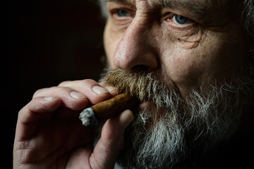 Senior bearded man smoking on balcony classic big cigar in detail