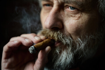 Senior bearded man smoking on balcony classic big cigar in detail