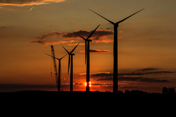 wind turbines at sunset with crane
