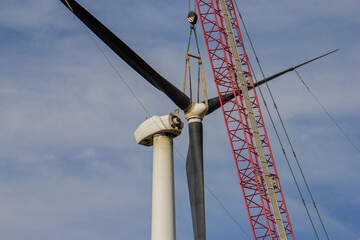 crane pulling blades off a wind turbine