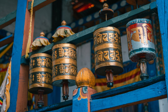 Paro, Bhutan - 16 September 2025: View of golden prayer wheels spinning gently against a backdrop of vibrant colours and intricate carvings at Kyichu Lhakhang Temple, Bhutan.