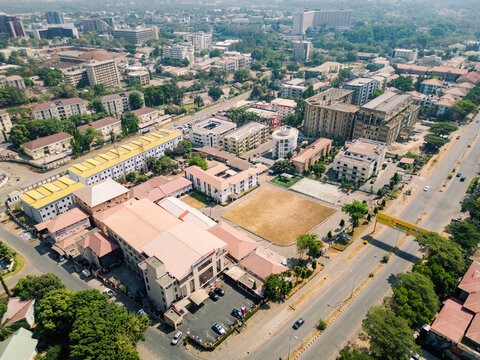 Aerial view of buildings standing proudly against the sky, lush greenery, and roads buzzing with life casting shadows across the urban landscape, Abuja, Federal Capital Territory, Nigeria.