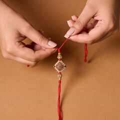 Woman tying traditional Rakhi thread with decorative charm  