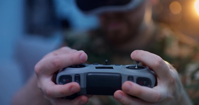 Man in camo attire hold rc controller for training simulation fly on FPV drone in VR glasses, Immersive virtual reality.
