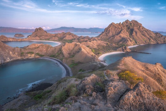 View of rugged mountains meeting turquoise waters, pristine beaches, and a serene sky create a striking contrast in Komodo, West Manggarai Regency, Indonesia.
