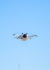 Fototapeta premium Quadcopter in flight against the sky. A small drone takes off above the ground.