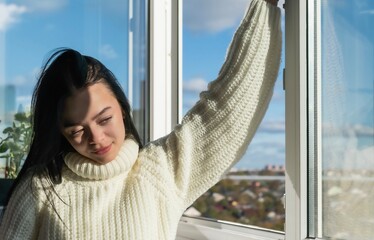 A young girl poses near a window in a house