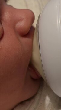 Extreme close-up of a newborn baby face while bottle feeding, infant drinking milk from a bottle, parenthood, childhood, baby healthcare, nursing, and newborn care. Video 4k