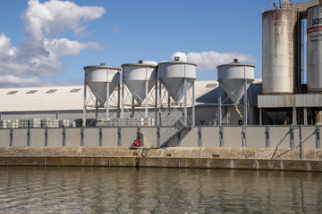 Obraz premium Industrial riverside area in Bamberg, Bavaria, Germany, along the Regnitz River with boat tour activity, waterfront infrastructure and urban landscape mixed with surrounding natural scenery.