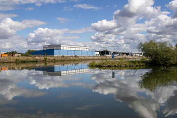 Industrial riverside area in Bamberg, Bavaria, Germany, along the Regnitz River with boat tour activity, waterfront infrastructure and urban landscape mixed with surrounding natural scenery.