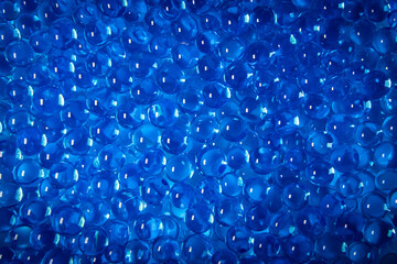 A close-up  photo of a pile of small blue hydrogel beads filled with water