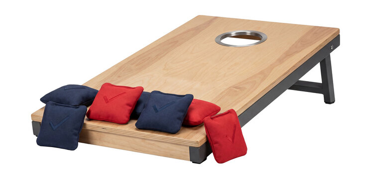 Cornhole game board with bean bags and a wooden platform.