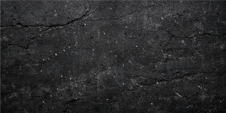 A dark and rough old black asphalt texture shows a weathered grey stone pattern on a grunge street road surface material with a detailed granite and concrete design wallpaper closeup