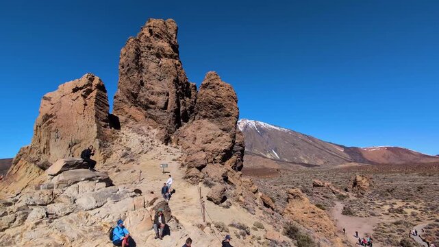 Tourists walks along the trails of ochre sand and basalt rocks that extend at the foot of the imposing Mount Teide in Teide National park