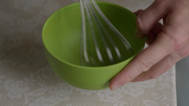 Close-up shot of a person mixing with a whisk in an empty bowl. Cooking preparation gesture, kitchen routine and simple domestic action before food preparation. High quality 4k footage