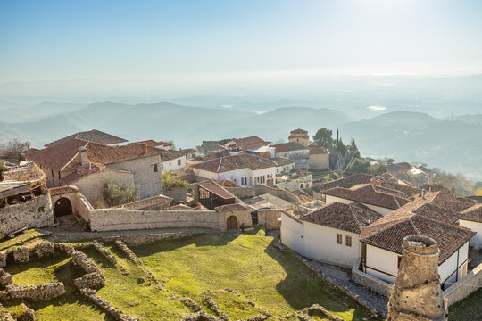 Ancient mountain settlement with traditional stone buildings, castle ruins and defensive walls overlooking a scenic Balkan landscape in daylight, Kruja, Albania