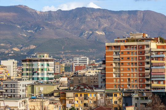 Residential apartment buildings and dense urban housing with mountains in background during daylight in capital city Tirana, Albania