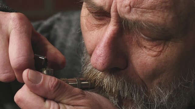 Older man smoking marijuana from metal pipe on balcony in detail video footage