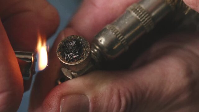 Older man smoking marijuana from metal pipe on balcony in detail video footage