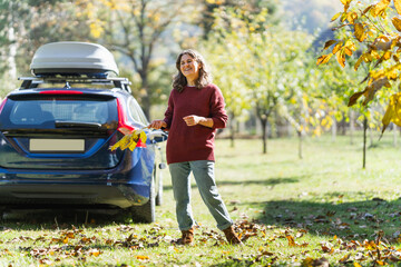 Woman traveler with backpack next to charging electric car
