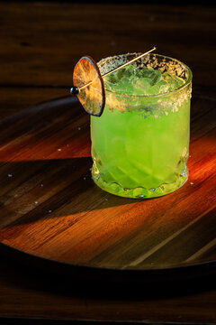 Bright Green Margarita on the rocks with salt and a dehydrated lime wheel with dramatic lighting