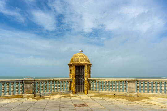 Traditional Stone Sentry Box on the Sea Walls of Cadiz Spain Historic Military Architecture Overlooking Atlantic Ocean with Stone Balustrade and Cloudy Sky