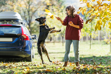 Woman with her dog next to charging electric car
