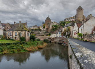 Fototapeta premium Semur-En-Auxois, France - 10 21 2025: Panoramic view of the rampart, old city reflecting on the water with autumn colors from bottom along Armancon river