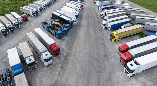 Aerial view of a large truck parking lot at a logistics hub, with multiple commercial semi trucks parked in organized rows