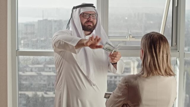 Rude Arabian man, throwing a hundred-dollar banknotes into a woman's face, a businesswoman, and inappropriate maintenance