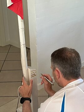 man painting on a flagpost with roller