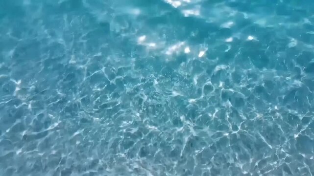 Abstract closeup of clear blue water surface with shimmering light reflections