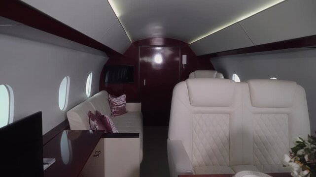 Luxurious private jet interior showcasing elegant seating, plush cushions, and a beautifully arranged dining table with floral centerpiece, illuminated by soft ambient lighting